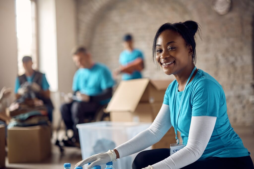 Young happy black woman volunteering at humanitarian aid center and looking at camera.